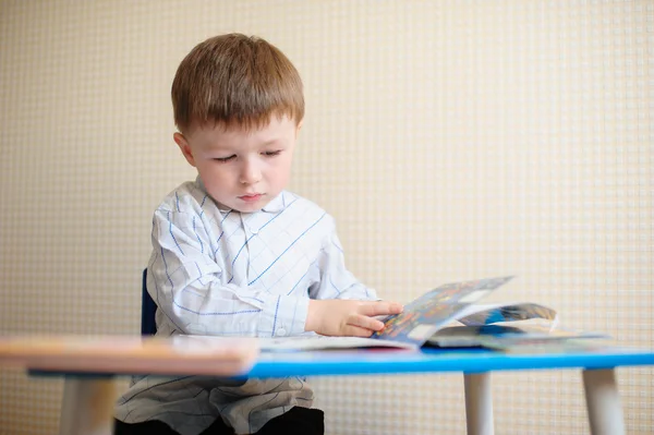 Little boy at the desk reading a book — Stock Photo, Image