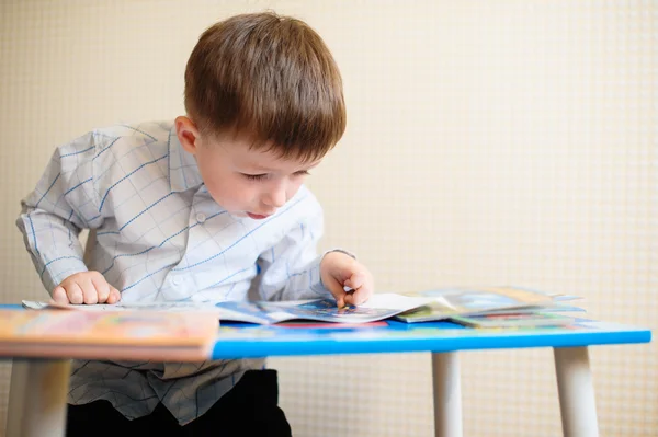 Little boy at the desk reading a book — Stock Photo, Image