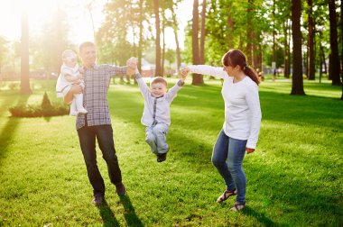 mutlu genç aile yaz parkta yürüyor