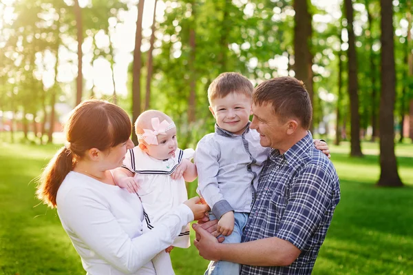 Gelukkige jonge familie wandelingen in het park van de zomer — Stockfoto