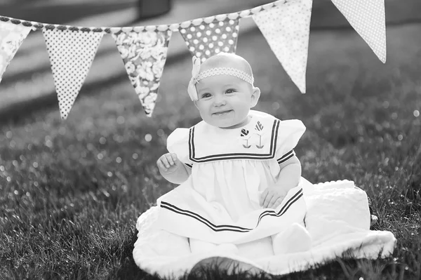 Niña feliz sentado en la hierba con banderas — Foto de Stock