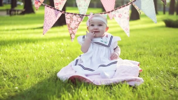 Милая маленькая девочка, сидящая на траве в солнечный летний день — стоковое видео
