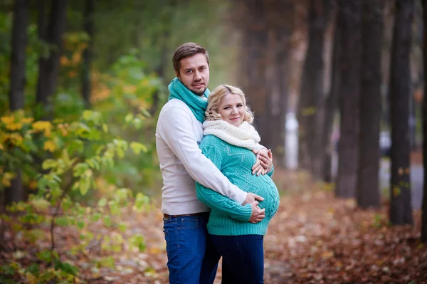 Marido y esposa embarazada están caminando en el parque de otoño — Foto de Stock