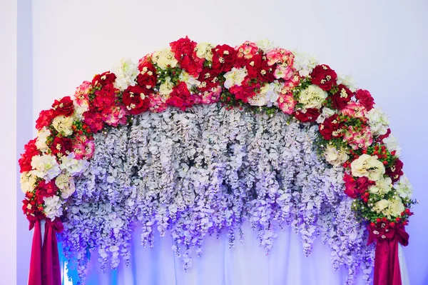 Hermoso arco de boda decorado con flores rosas y rojas en el interior — Foto de Stock