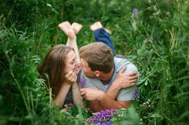Genç mutlu güzel çift erkek ve kadın açık havada yeşil çim üzerinde yalan