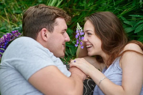 Young happy beautiful couple man and woman lying outdoors on green grass — Stock Photo, Image