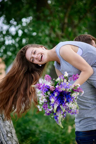 Beautiful woman with a bouquet of lupine on the mans shoulder — Stock Photo, Image