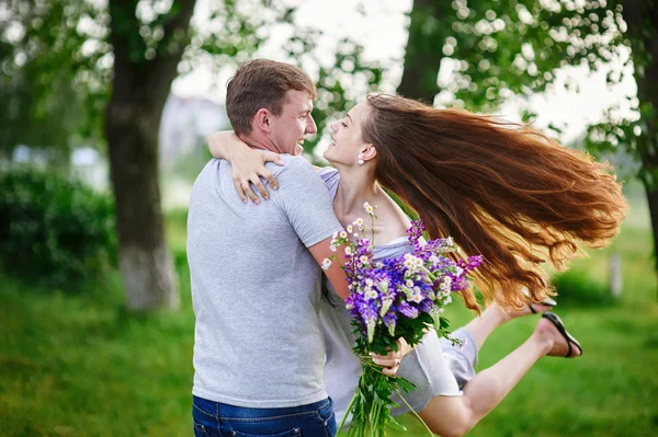 Hermosa mujer con el pelo largo y un hombre feliz abrazándose en el campo — Foto de Stock