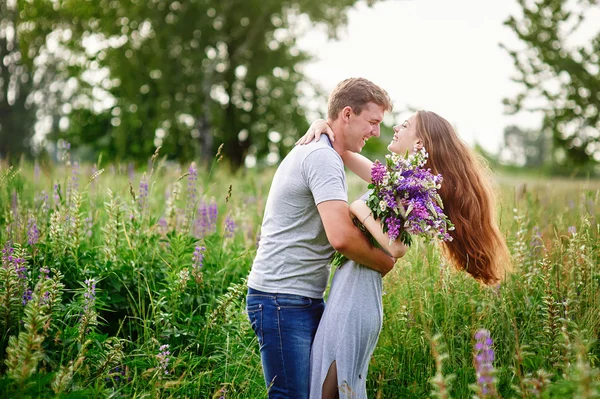 Krásná žena s dlouhými vlasy a šťastný muž, objímat v poli — Stock fotografie