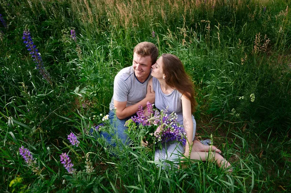 Jeune heureux beau couple assis dans la prairie verte — Photo