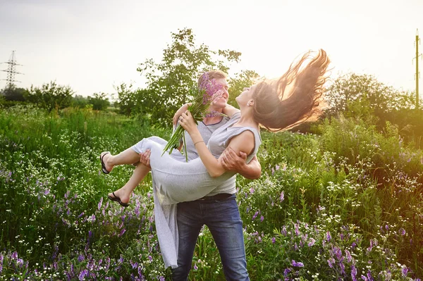 Happy love man holding a woman on his arms in field — Stock Photo, Image