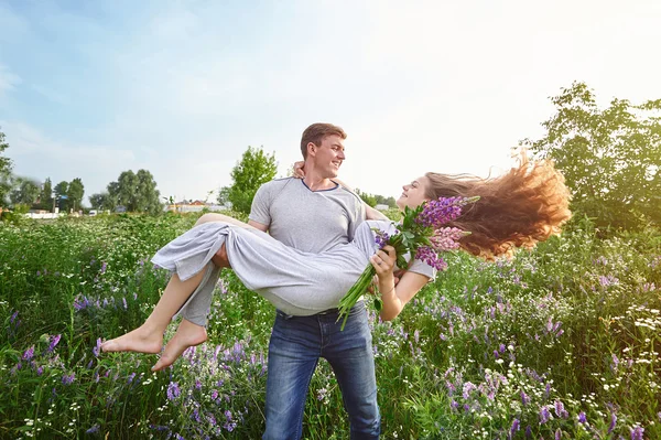 Gelukkig liefde man die een vrouw op zijn armen in veld — Stockfoto