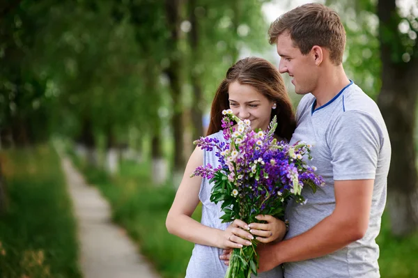 Beautiful couple in love walking with a bouquet of wildflowers — Stock Photo, Image