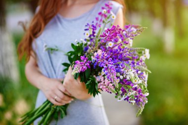 Bir buket mavi kurt çiçek tutan kadın