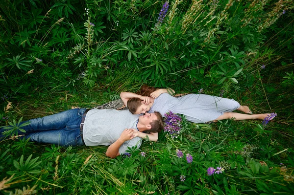 Young happy beautiful couple man and woman lying outdoors on green grass — Stock Photo, Image