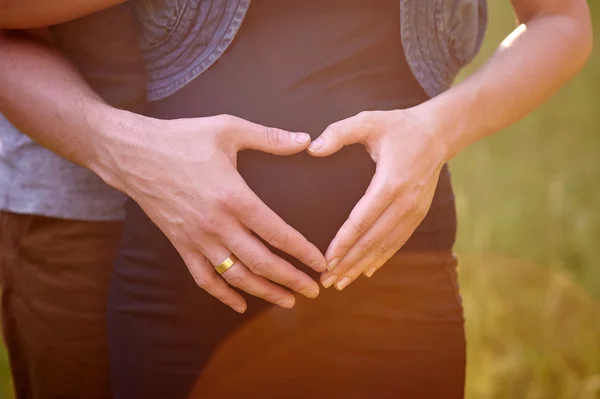 Barriga grávida com os dedos Símbolo do coração — Fotografia de Stock