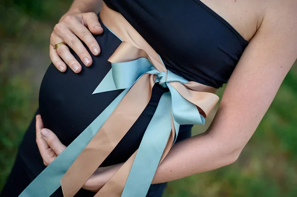 Kobieta w ciąży i mąż, trzymając się za ręce na brzuchu — Zdjęcie stockowe
