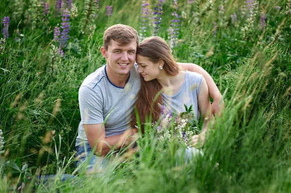 Young happy beautiful couple sitting in green meadow — Stock Photo, Image