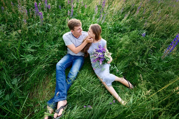 Jovem casal bonito feliz sentado no prado verde — Fotografia de Stock