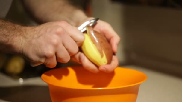 Closeup view of a male hand peeling an organic potato — Stock Video