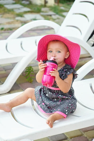 Bambina in cappello rosso siede su un lettino — Foto Stock