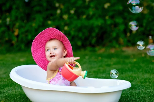 Kleines Mädchen badet in einer Badewanne mit Seifenblasen — Stockfoto