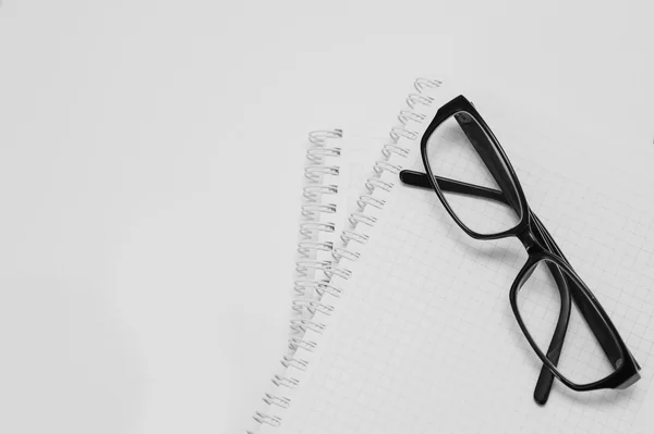 Black plastic glasses on the opened notepad — Stock Photo, Image