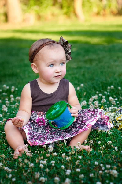 Çim ve yiyor çerezleri üzerinde oturan küçük kız — Stok fotoğraf