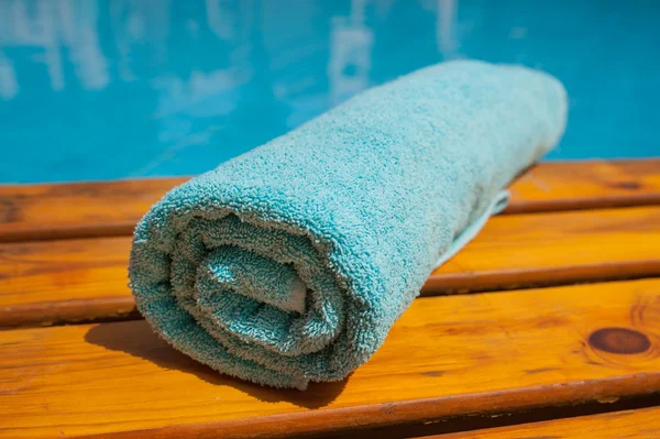 Azul toalha enrolada deitada em uma espreguiçadeira perto da piscina — Fotografia de Stock