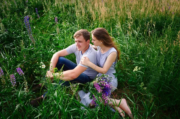 Pareja enamorada sentado en verde hierba verano prado — Foto de Stock