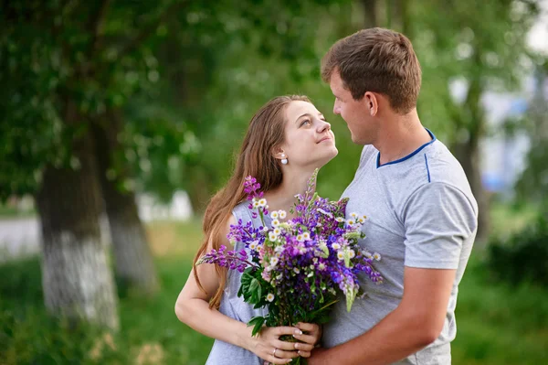 Man and woman meet in park with bunch of flowers — Stock Photo, Image