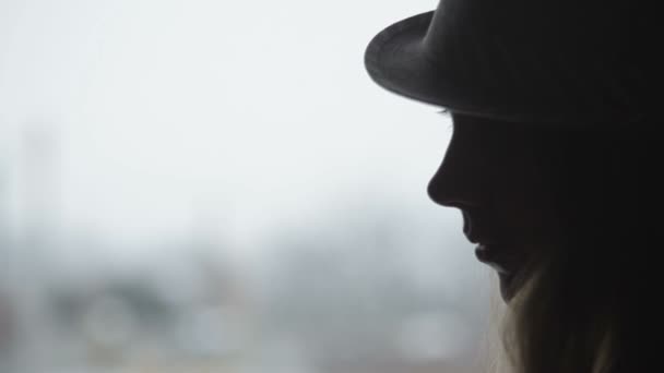 Vrij casual vrouw stond bij venster, het dragen van hoed — Stockvideo