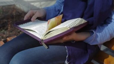 kadın parkta bir bankta oturmuş ve İncil'in kitap okuma