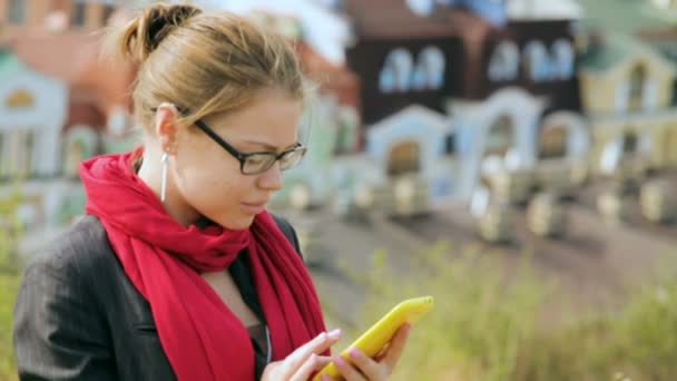 Hermosa mujer en gafas está escribiendo en el teléfono inteligente — Vídeo de stock