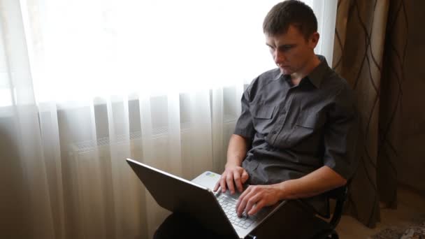 Мужчина играет на ноутбуке в комнате — стоковое видео