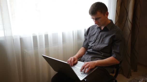 Hombre jugando en un ordenador portátil en la habitación — Vídeos de Stock