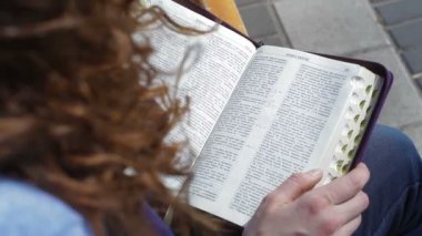 kadın parkta bir bankta oturmuş ve İncil'in kitap okuma