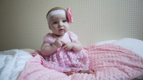 Cute beautiful baby girl sitting on a bed in pink dress — Stock Video