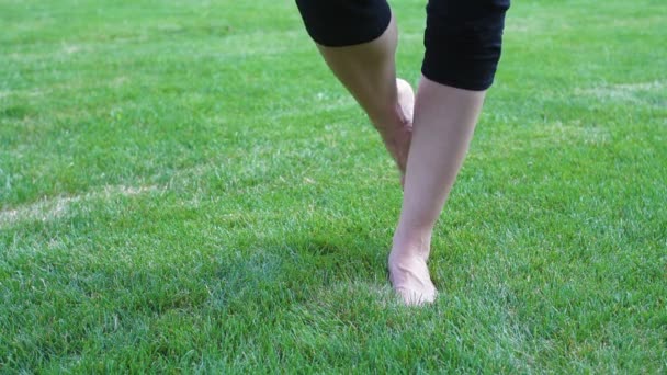 Красивая молодая женщина бежит босиком по траве на летнем лугу — стоковое видео
