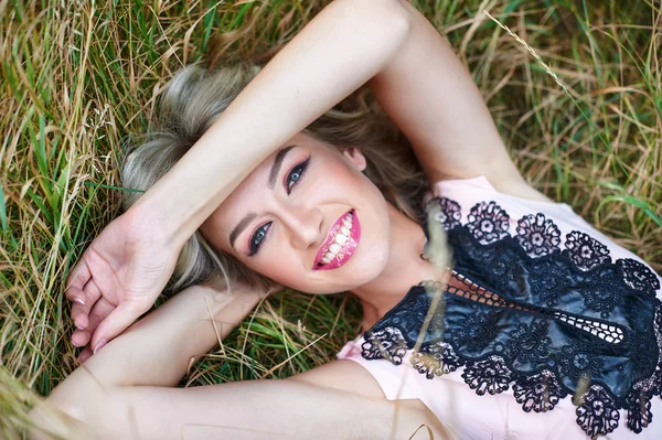 Hermosa mujer sonriendo y acostado en la hierba — Foto de Stock