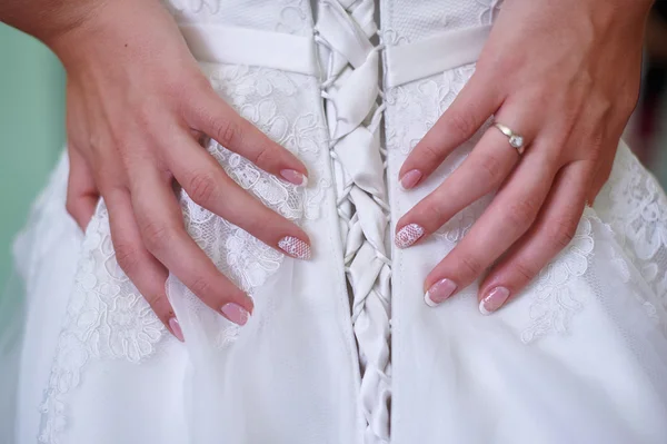 Hermosas manos femeninas con manicura contra un vestido blanco — Foto de Stock