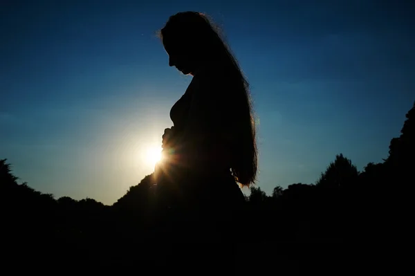 Silhouette of a pregnant woman against the backdrop on sunset — Stock Photo, Image