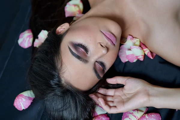 Портрет красивой молодой женщины, лежащей на редких лепестках роз — стоковое фото