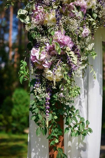 Wedding arch decorated with flowers and glass hanging vases — Stock Photo, Image