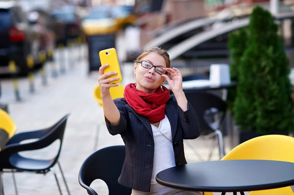 Gözlüklü genç kadın selfie kafede yapar. — Stok fotoğraf