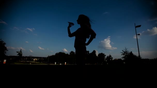 Silhouette einer Frau, die ein Papierflugzeug in der Hand gegen den Himmel hält — Stockvideo