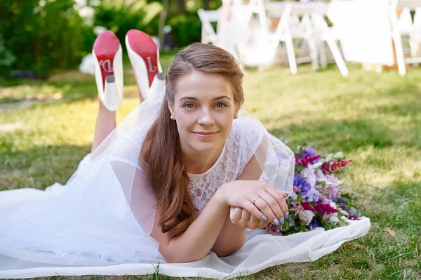 Bride lying on the grass in the spring garden — Stock Photo, Image