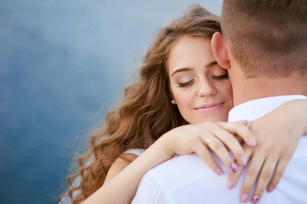 Young groom and bride hugging on the background of lake — Stock Photo, Image