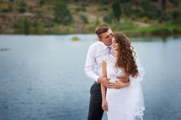 Hermosa pareja joven caminando cerca del lago en el día de la boda —  Fotos de Stock