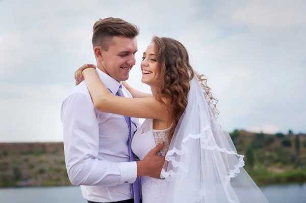 Vackra unga par promenader nära sjön på bröllopsdagen — Stockfoto